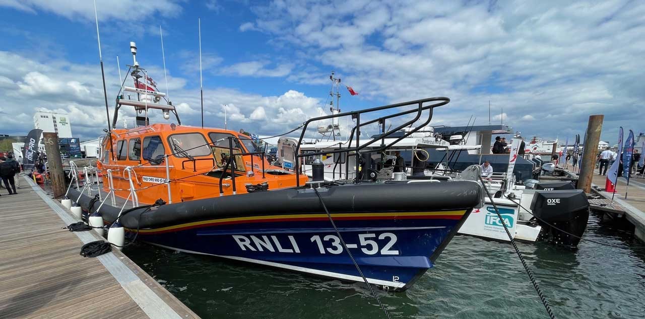 RNLI rescue lifeboat docked at the marina under a cloudy blue sky.