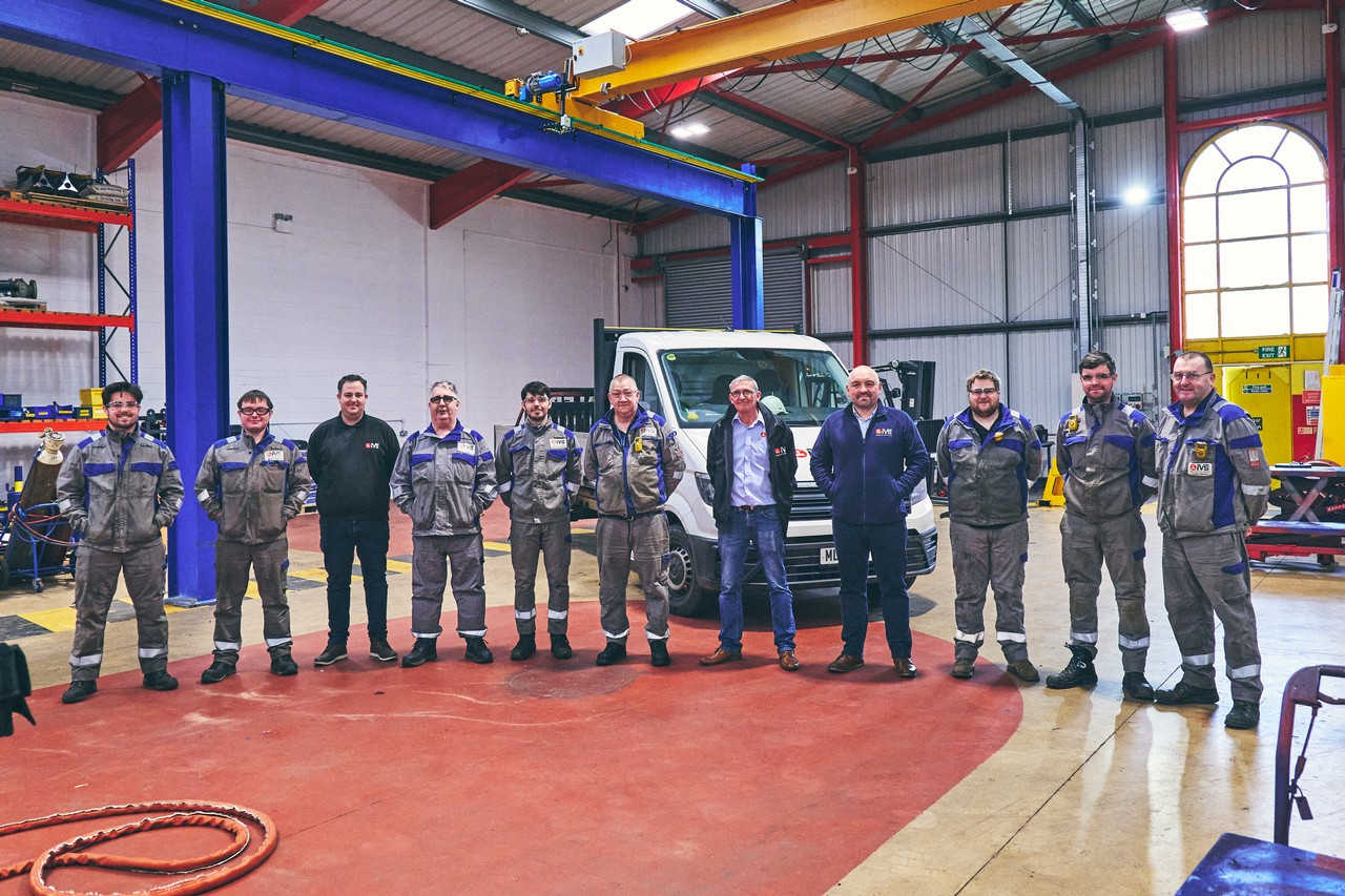 Group of IVS technicians posing in a well-equipped industrial maintenance workshop.