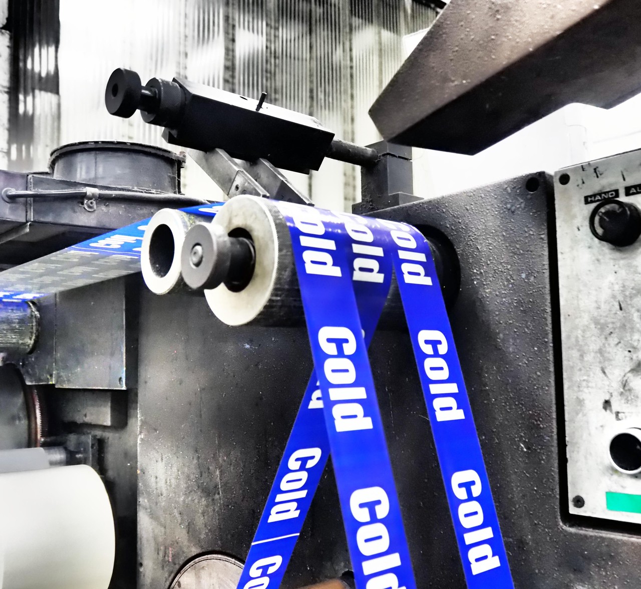 Industrial tape machine featuring rollers and blue 'Cold' labelled tape.