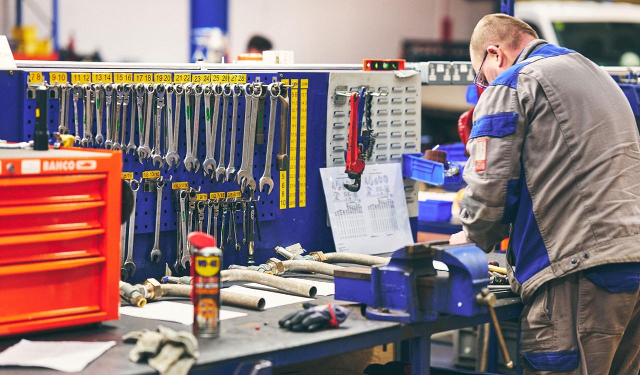 Workshop with organised tool racks and a technician working.