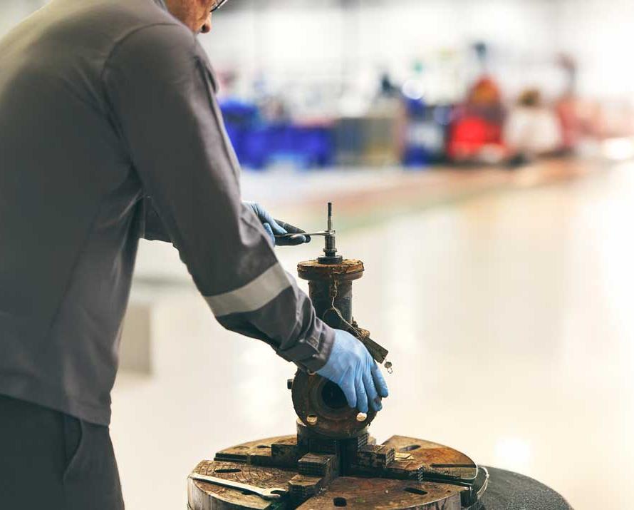 Technician in protective gloves inspecting an industrial valve.