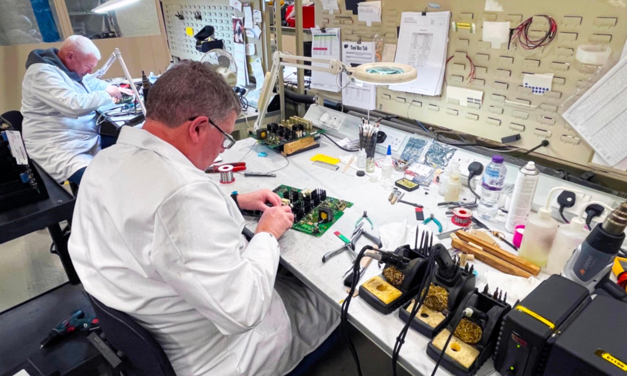 Specialist B2B Manufacturing - Technicians repairing and testing electronic equipment in a well-equipped workshop.